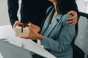 Young businessman giving his colleague present in office. Young man surprise beautiful businesswoman in office. photo