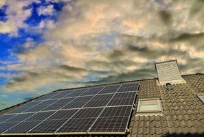 solar paneles productor limpiar energía en un techo de un residencial casa con un puesta de sol cielo. foto