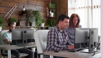 Young business man with his colleague working on a new application. Manager helping intern in the background. video