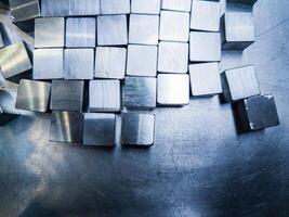 pile of small machined shiny steel cubes on metal surface photo