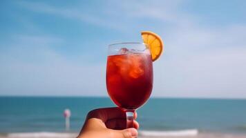AI generated caucasian hand holding glass of red fruit cocktail on blurry sea horizon background at sunny day, neural network generated image photo