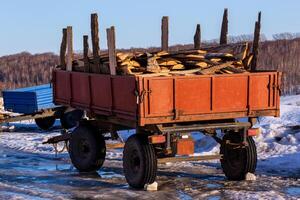 old rustic trailer with firewood lumber leftovers at winter daylight photo