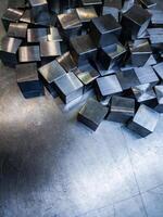 pile of small machined shiny steel cubes on metal surface photo