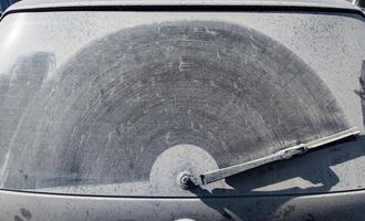 dusty rear window of the car with wiper trace on layer of dirt photo