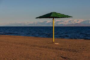 rigid steel umbrella on beach of mountain lake at sunny evening photo