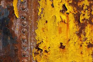 beautifully rusted rivetted sheet metal with leftovers of yellow paint texture and full-frame background photo