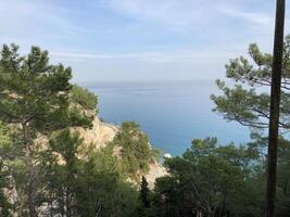 Abandoned scenic old road along the sea and cliffs, view from above from the cliff through the trees photo