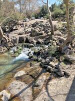 The stream of water flows through large stones and forms a small waterfall photo