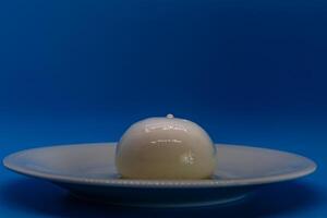 Burrata cheese Sitting on Plate on Blue Background photo