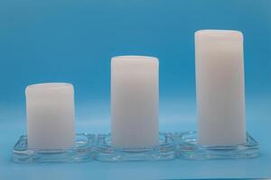 Three White Candles on Blue Background in Ascending Order photo