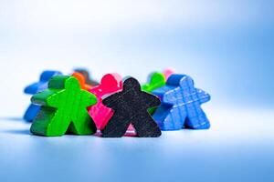 A varied collection of wooden figures in different colors, arranged in a seated position next to one another. photo