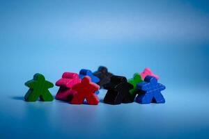 A varied collection of wooden figures in different colors, arranged in a seated position next to one another. photo