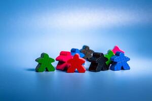 A varied collection of wooden figures in different colors, arranged in a seated position next to one another. photo