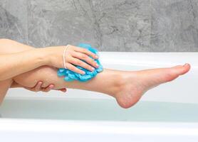 Woman washing her body in the bath. Close-up of female legs in a bathtub photo