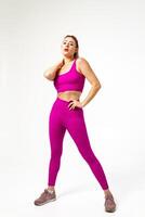 Woman in vibrant pink sports outfit with one hand on neck and other on hips photo