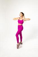 Woman in vibrant pink sports outfit with hands holding tank top straps photo