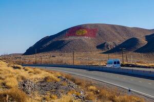 el bandera de Kirguistán es dibujado en un montaña a soleado otoño día, exhibiendo el de la nación orgullo y espíritu. foto