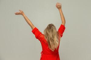 Blonde woman turned her back to the camera and waves her arms.Isolated on a gray background. photo