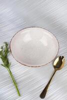 White empty deep clay plate with a spoon on a white background. photo