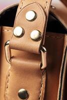 parte de un bolso hecho de marrón genuino cuero con un metal fijación para el manejar. foto