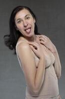 A middle-aged woman in lingerie shows her tongue playfully. photo