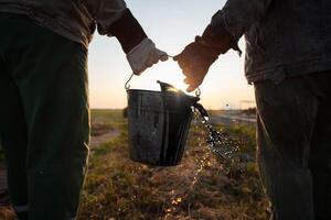 Workers carry a bucket of spilled extracted oil. Discover oil fields. Black gold. photo