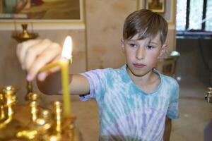 A boy lights candles in an Orthodox church. photo