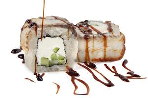 Sushi closeup isolated on white background. Sushi roll with graham rice, Philadelphia cheese and celery topped with soy sauce. Japanese restaurant menu. photo