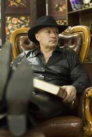 Elderly man in a hat in a leather chair photo