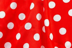 Background red satin fabric with white polka dots. photo