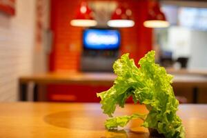 Green lettuce leaf on blurred kitchen background. Healthy eating and vegetarianism. photo