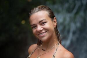 Close-up portrait of a beautiful girl with wet hair against the backdrop of a waterfall. photo