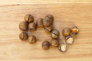 Roasted macadamia seeds scattered on a wooden table. The seeds have a nutty flavor and texture. Rich in many nutrients. Soft and selective focus. photo