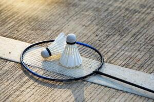 blanco volante 2 metido lado por lado en un bádminton raqueta con un cemento fondo.suave y selectivo atención foto