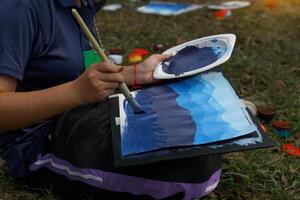 The students used brushes to paint the colors of the distant mountain range from light blue to dark blue. Follow the example the teacher gives you. photo