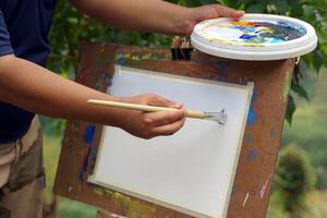 An art teacher teaches landscape painting with watercolors to children attending art camp. Soft and selective focus. photo