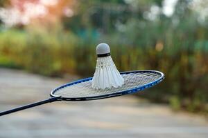 White cream badminton shuttlecocks on badminton rackets, blurred trees background, concept for outdoor badminton playing in free times, soft and selective focus. photo