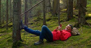 Man in nature. Outdoor travel concept. Tourist guy resting on moss in a beautiful forest. photo