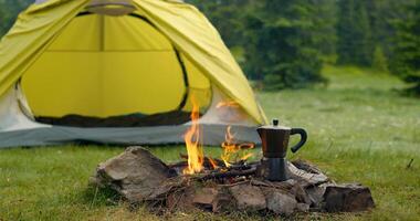 Tent and bonfire on the forest lawn in the mountains. Travel concept photo