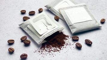 Drip coffee paper bags with coffee beans on a grey concrete background video