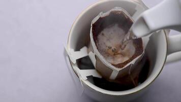 heiß Wasser gegossen in ein Tasse von geröstet Kaffee zu produzieren frisch tropfen Kaffee. Herstellung Kaffee mit tropfen Kaffee Tasche video