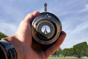 selective focus shot person holding camera lens on effil tower tourist taking a picture with camera lens on eiffel tower photo