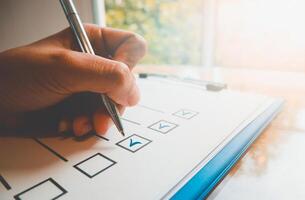 Close- up hand holding pen on check list paper and the format for filling in information in business concept,vintage style and softtone photo