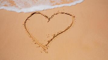 Drawing on the sand. Drawing heart. The sea shore is washed by a wave. photo