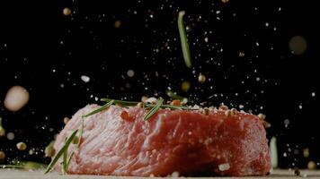 Close-up of falling salt and pepper on raw beef steaks on table, freeze motion. photo