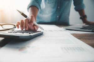 business person sitting at a desk at an office By using the calculator to work. Business Concept Analysis and Planning photo