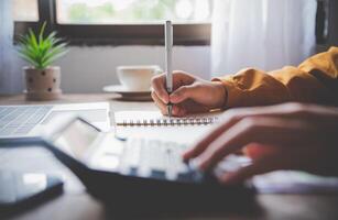 business person sitting at a desk at an office By using the calculator to work. Business Concept Analysis and Planning photo