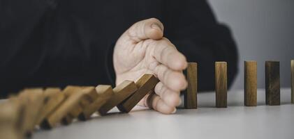 close-up hand The hand of a businessman who is stopping or preventing a falling block.Risk protection concept,Eliminating the risk photo