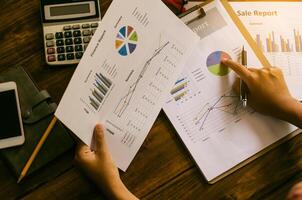 Businessman holding paperwork on the table and analyzing investment chart working in office. Business work concept. photo