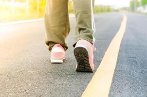 Woman jogging on road close up on shoes in the evening photo